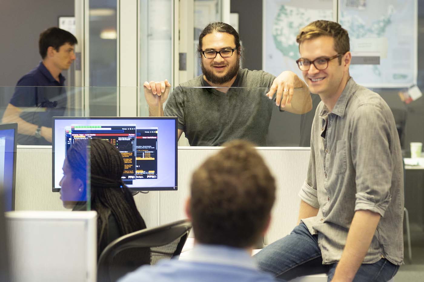 Colleagues gather around a work station.